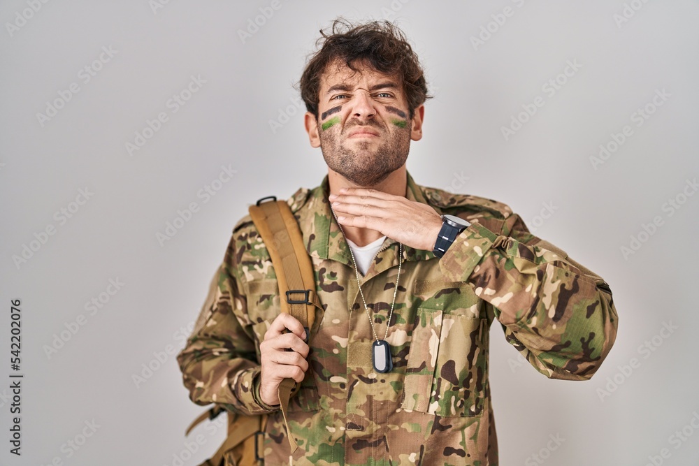 Hispanic young man wearing camouflage army uniform cutting throat with hand as knife, threaten aggression with furious violence