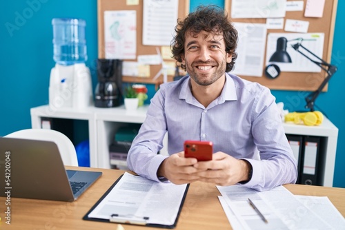 Young hispanic man business worker using smartphone working at office