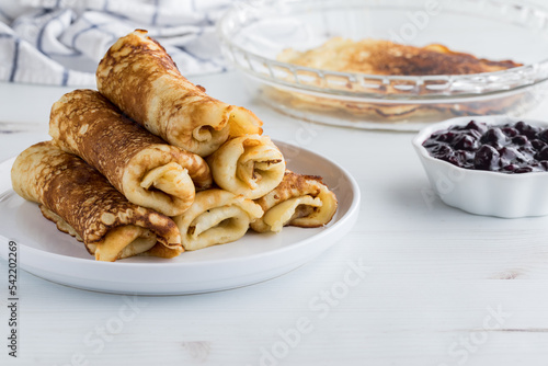 A pile of freshly made rolled crepes served with sweet blueberry sauce.