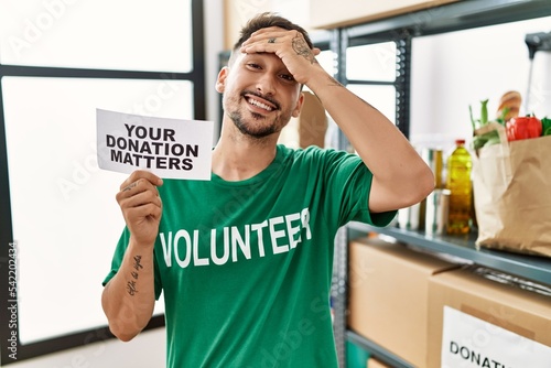 Young volunteer man holding your donation matters banner stressed and frustrated with hand on head  surprised and angry face