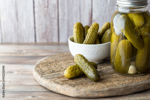 A jar of homemade dill pickles with a bowl full and pickles in front. photo