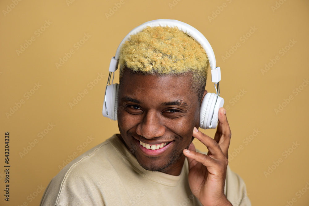Φωτογραφία Handsome young African man listening to his favourite playlist in white headphones, enjoying his best song moment