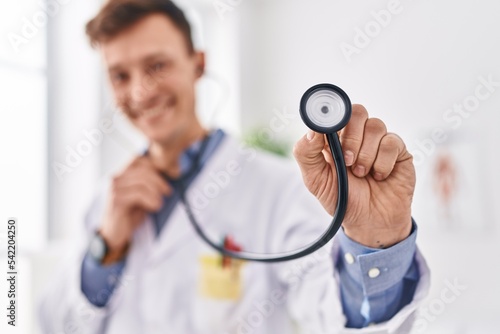 Young man doctor smiling confident holding stethoscope at clinic