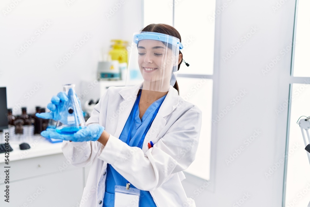 Young hispanic woman wearing scientist uniform holding test tube at laboratory Young hispanic woman wearing scientist uniform holding test tube at laboratory