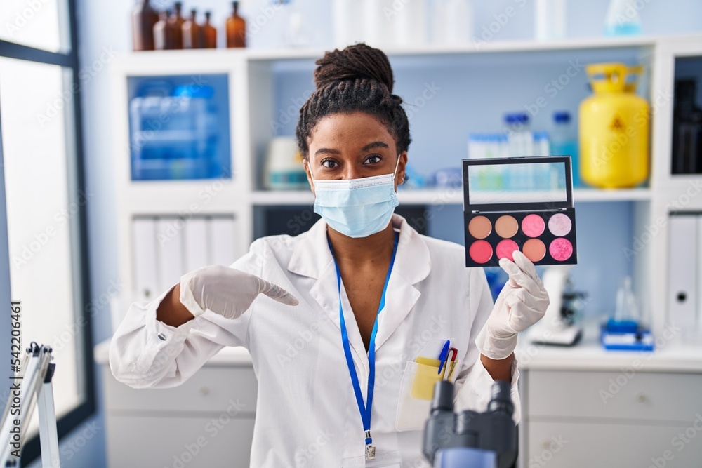 Young african american with braids working at scientist laboratory doing make up pointing finger to one self smiling happy and proud