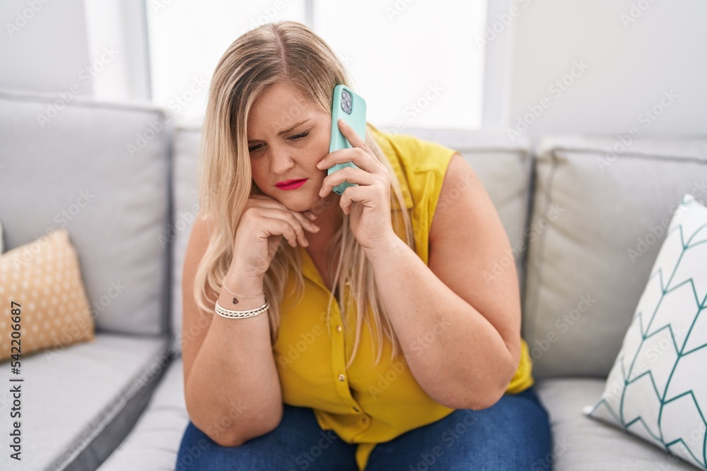 Young woman talking on the smartphone with worried expression at home Young woman talking on the smartphone with worried expression at home