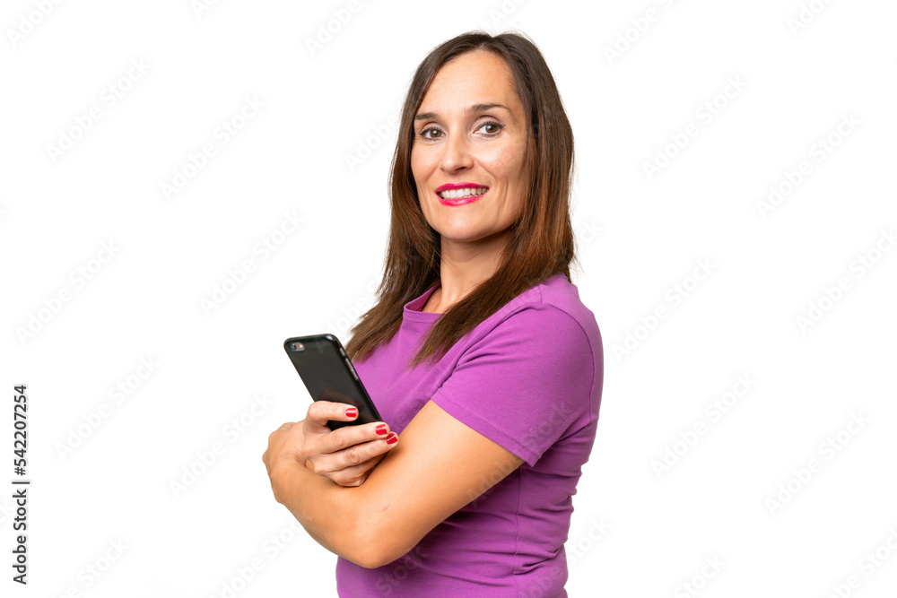 Middle-aged caucasian woman over isolated background holding a mobile phone and with arms crossed Middle-aged caucasian woman over isolated background holding a mobile phone and with arms crossed