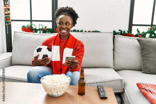 African american woman supporting soccer team using smartphone at home © Krakenimages.com