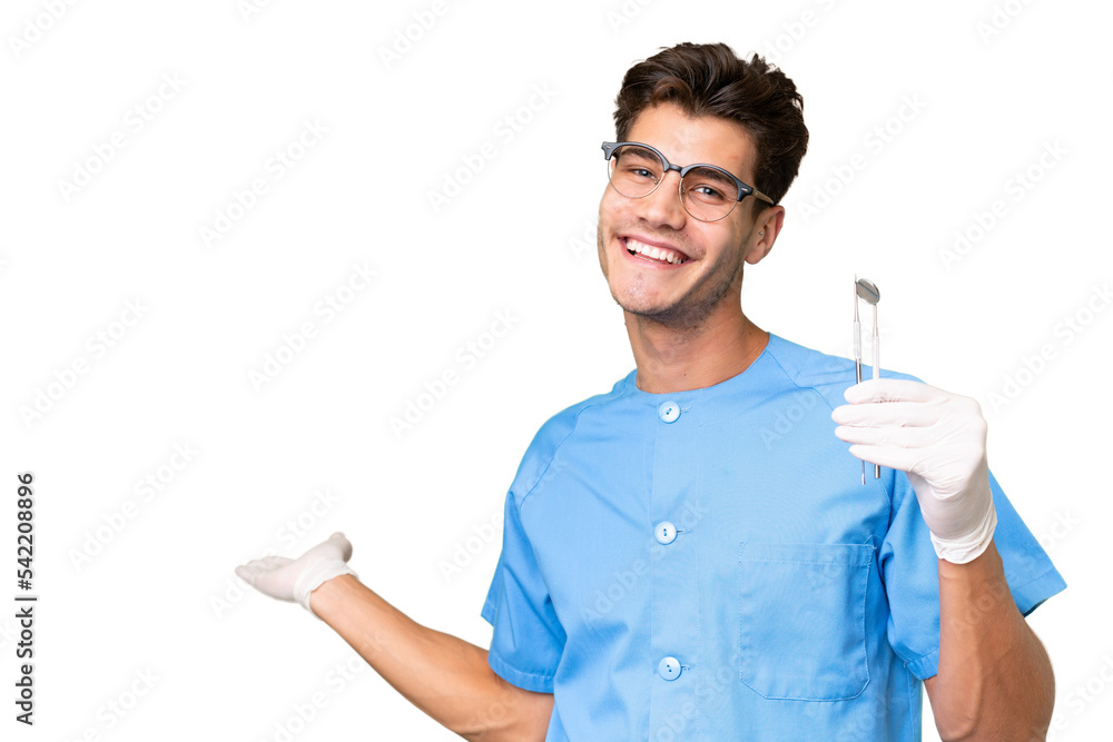 Young dentist man holding tools over isolated background extending hands to the side for inviting to come Young dentist man holding tools over isolated background extending hands to the side for inviting to come