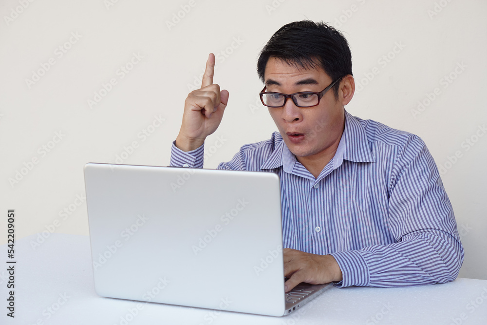 Handsome Asian man office worker feels surprised and got the idea during surfing internet on laptop computer. Point finger up. Concept : work online. Daily Life digital, technology smart device. Handsome Asian man office worker feels surprised and got the idea during surfing internet on laptop computer. Point finger up. Concept : work online. Daily Life digital, technology smart device.