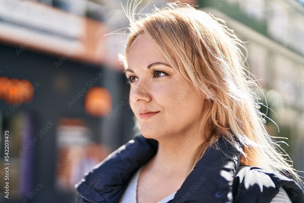 Young blonde woman looking to the side with serious expression at street Young blonde woman looking to the side with serious expression at street
