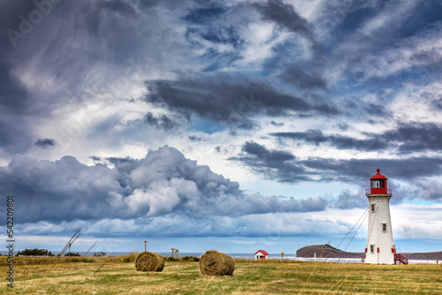 The Anse a la Cabane, or Millerand lighthouse of Havre Aubert, in Iles de la Madeleine, or the Magdalen Islands, Canada. This is the tallest and oldest working ighthouse of the archipelago. Stormy sky