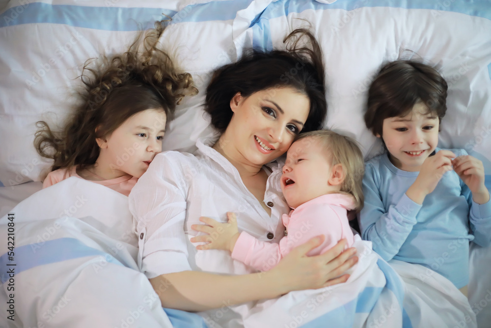 A family with children having fun on the bed under the covers during the Christmas holidays. A family with children having fun on the bed under the covers during the Christmas holidays.