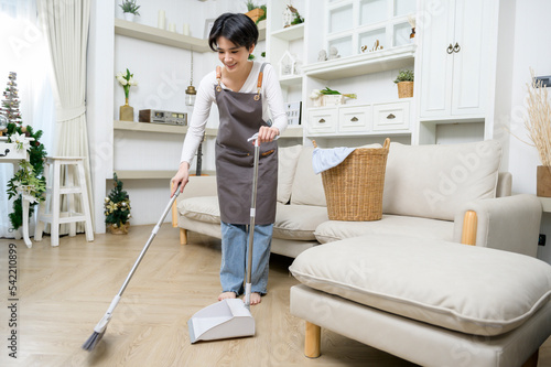Happy Asian young woman sweeping the floor to cleaning house, healthy lifestyle concept