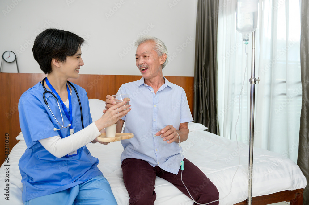 Obraz premium Asian nurse giving an elderly medicine at senior healthcare center.