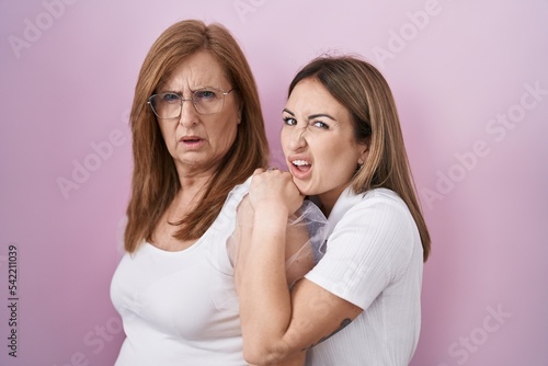 Hispanic mother and daughter wearing casual white t shirt clueless and confused expression. doubt concept.