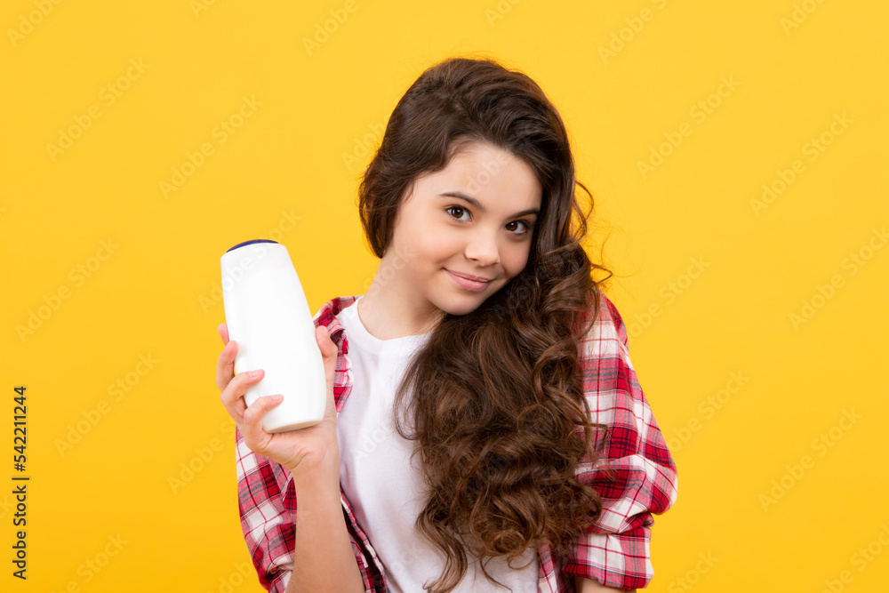 Child teen girl with shampoos conditioners and shower gel. Long hair care of teenager. Presenting cosmetic product, shampoo bottle. Happy teenager, positive and smiling emotions of teen girl. Child teen girl with shampoos conditioners and shower gel. Long hair care of teenager. Presenting cosmetic product, shampoo bottle. Happy teenager, positive and smiling emotions of teen girl.