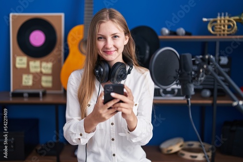 Young caucasian woman artist smiling confident using smartphone at music studio