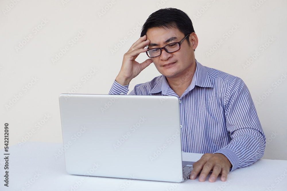 Asian middle-aged man office worker feels heachache, looks serious, think and plan something during working on laptop computer. Concept : Health problems , work with data. Asian middle-aged man office worker feels heachache, looks serious, think and plan something during working on laptop computer. Concept : Health problems , work with data.