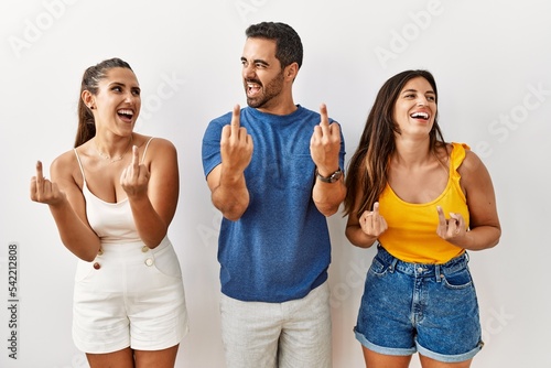 Group of young hispanic people standing over isolated background showing middle finger doing fuck you bad expression  provocation and rude attitude. screaming excited