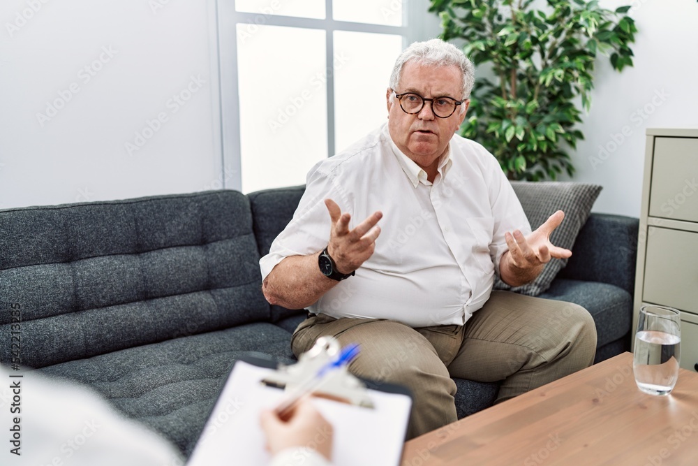 Middle age grey-haired man having psychology session at psychology clinic Middle age grey-haired man having psychology session at psychology clinic