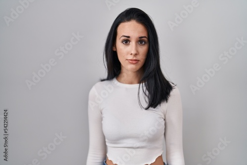 Hispanic woman standing over isolated background relaxed with serious expression on face. simple and natural looking at the camera.