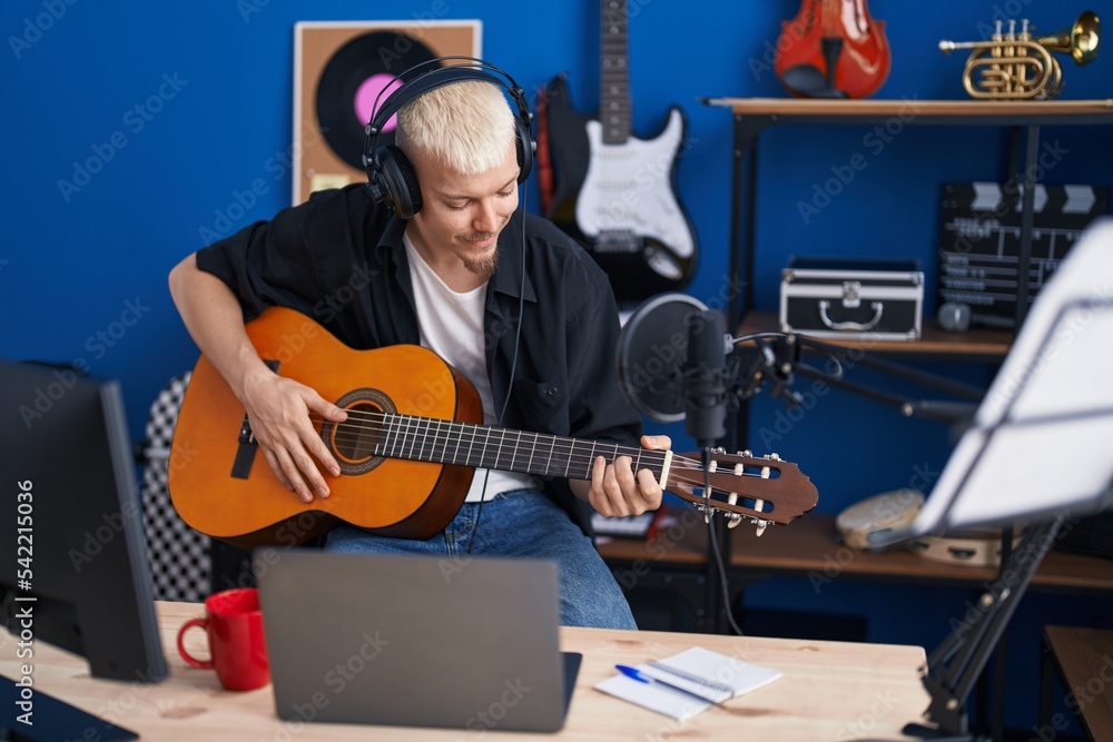 Obraz premium Young caucasian man musician playing classical guitar at music studio