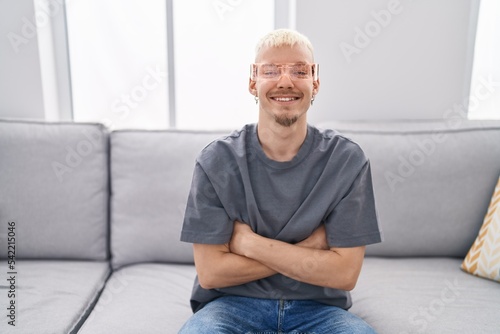 Young caucasian man wearing virtual reality glasses happy face smiling with crossed arms looking at the camera. positive person.