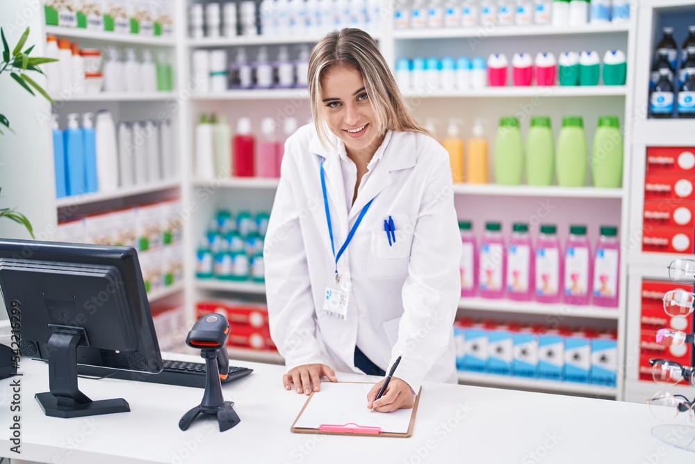 Young blonde woman pharmacist writing on document at pharmacy Young blonde woman pharmacist writing on document at pharmacy