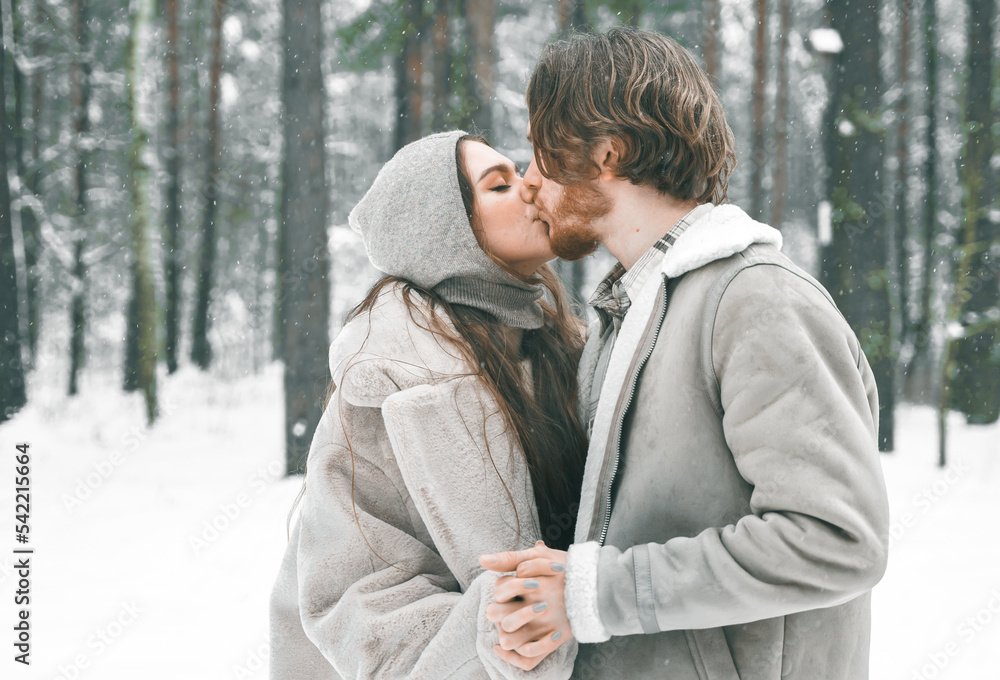 Love romantic young couple. Guy hugging kissing girl in snowy winter forest. Walking,having fun in trees, laughing. Stylish clothes,fur coat,jacket,woolen shawl. Snow lovestory. Romantic date,weekend