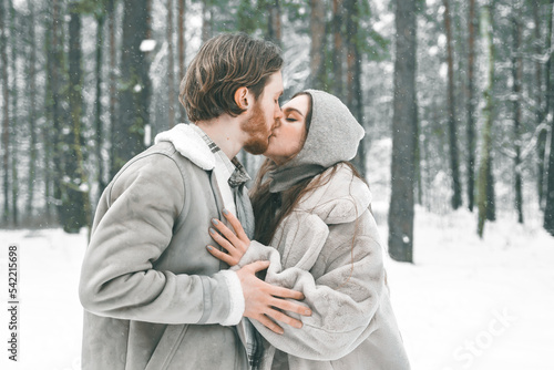 Love romantic young couple. Guy hugging kissing girl in snowy winter forest. Walking,having fun in trees, laughing. Stylish clothes,fur coat,jacket,woolen shawl. Snow lovestory. Romantic date,weekend © velirina