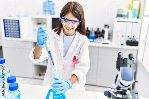 Young hispanic girl working using pipette at laboratory