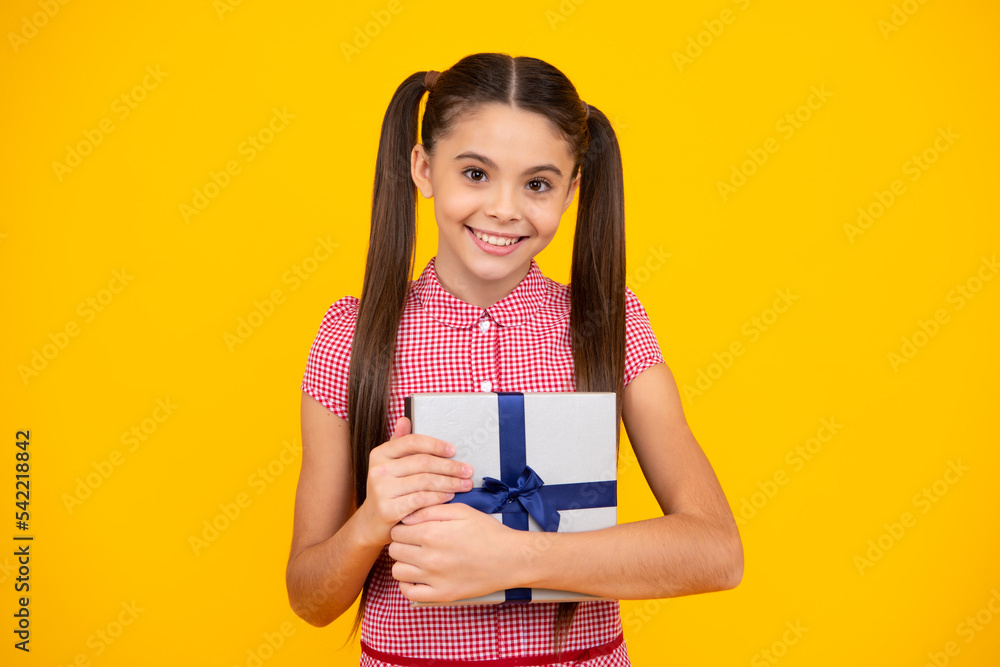 Happy teenage girl. Teenager child holding gift box on isolated yellow background. Gift for kids birthday. Christmas or New Year present box. Smiling kids emotions. Happy teenage girl. Teenager child holding gift box on isolated yellow background. Gift for kids birthday. Christmas or New Year present box. Smiling kids emotions.