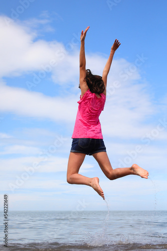 Happy  girl jumping and rejoicing happy by the sea in summer