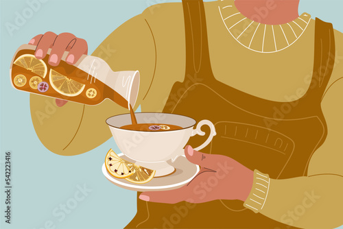 Woman holding a decanter of tea with lemon and orange slices. Winter and autumn cozy concept with a hot cup of warm drink.  Aromatic warming drink with fruits. 