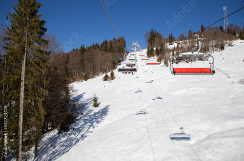 lift carrying unrecognizable skiers to the top of a snow-covered mountainside. cold winter sunny day, outdoor activities. Ski training. Winter sports. Seasonal winter joys