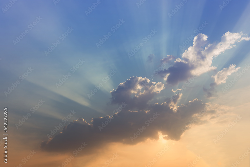 Sunset sky background, beams of sunlight shining through the clouds.