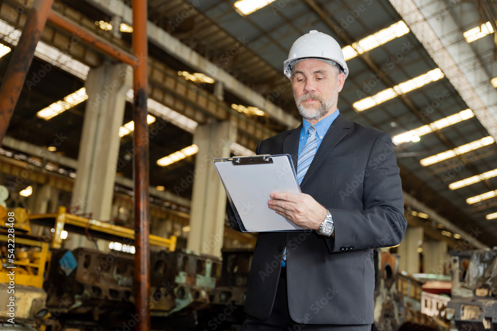 A businessman checks on-site maintenance work at an old factory A businessman checks on-site maintenance work at an old factory