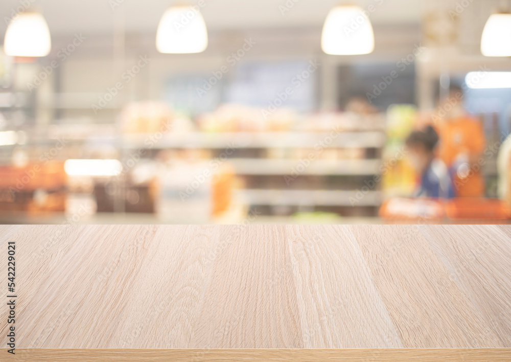 Wood table top on blur of supermarket product shelf background.business and shopping