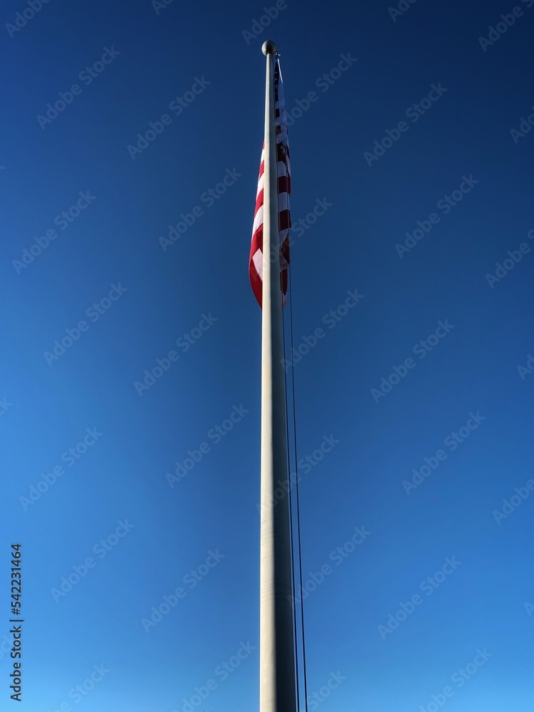 Star Spangled Banner American United States USA flag flying high and low, Side View with No Wind on a calm windless day on a flag pole with no clouds on a beautiful sunny day.  Vertical Framed Photo.