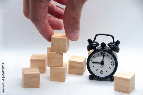 Blank wooden cubes and black alarm clock on white background with customizable space for text or ideas. photo