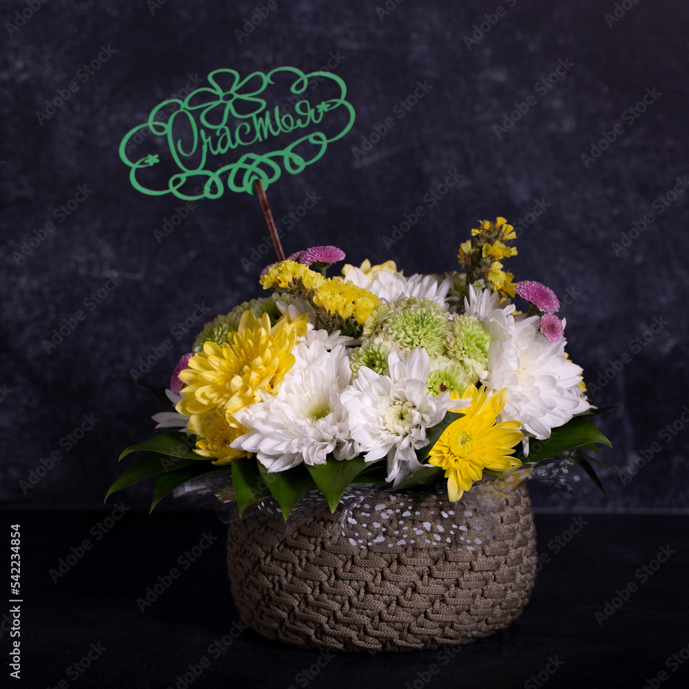 Naklejka premium flowers in a knitted basket stand on a dark background. a bouquet of flowers. a gift in the basket. handmade work.