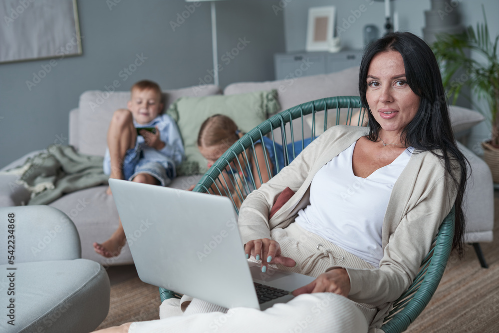 woman using laptop with interest at home while child relax on sofa woman using laptop with interest at home while child relax on sofa