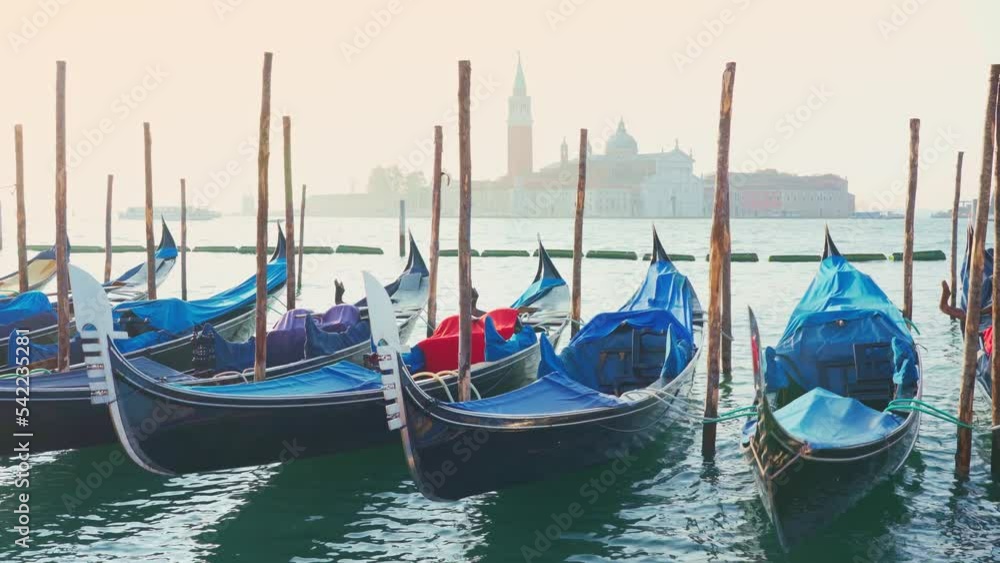 Gondolas at sunrise with San Giorgio Maggiore in the background, a swinging boat on the shore; no people Gondolas at sunrise with San Giorgio Maggiore in the background, a swinging boat on the shore; no people