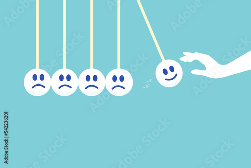 hand let smile face pendulum ball to hit other sad faces. concept of happiness or positive thinking and sadness.