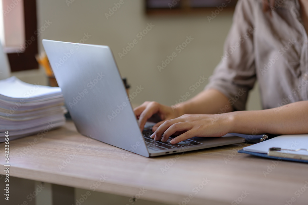 Fototapeta premium Woman hand who are actively typing and concentrate on work using laptop computer at the office.