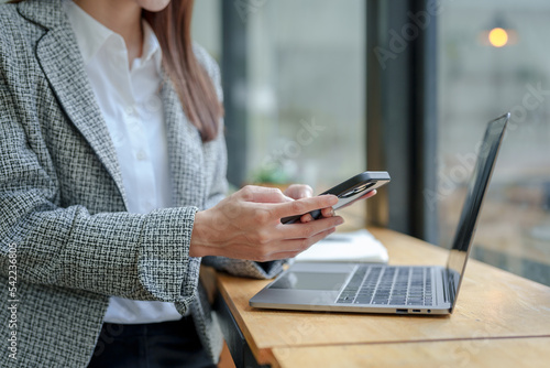 Close-up of a woman using a smartphone to do business with customers via messaging app LINE, conduct financial transactions or use social media. photo