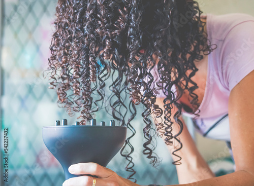 Close-Up of a woman bending over and drying her curly hair with a hair diffuser