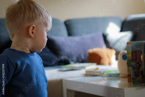 little boy playing on sofa with books and stuffed animals 