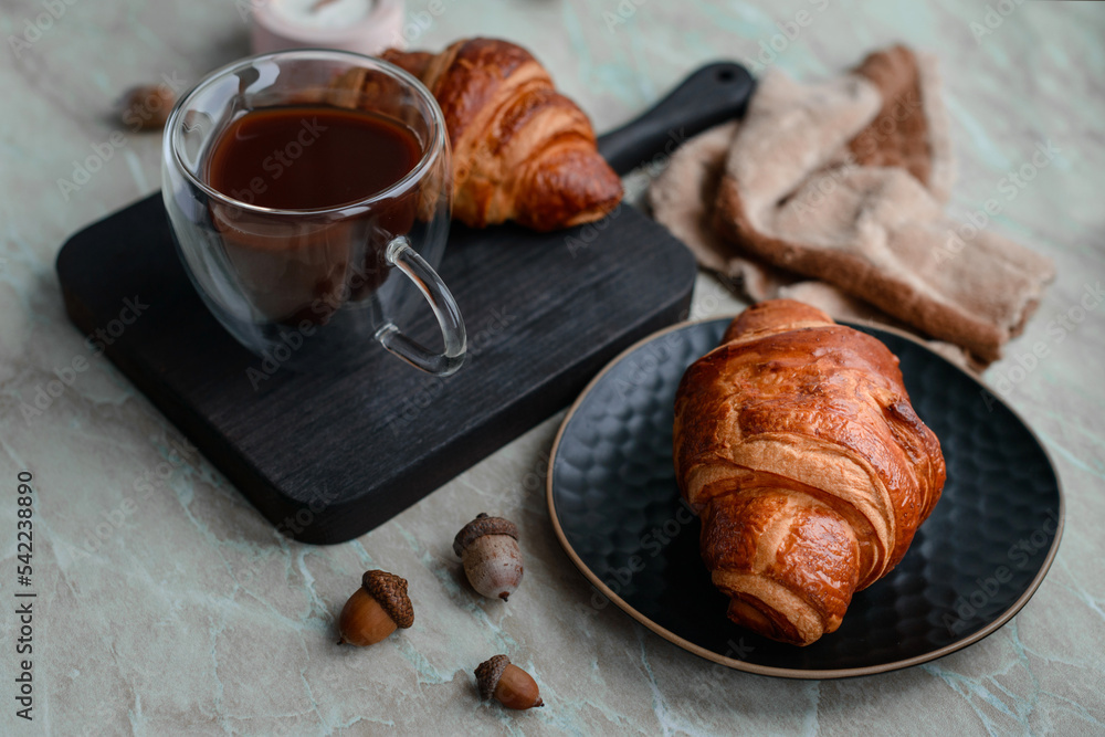 Delicious crispy croissant with chocolate with a cup of invigorating coffee on a light concrete background Delicious crispy croissant with chocolate with a cup of invigorating coffee on a light concrete background